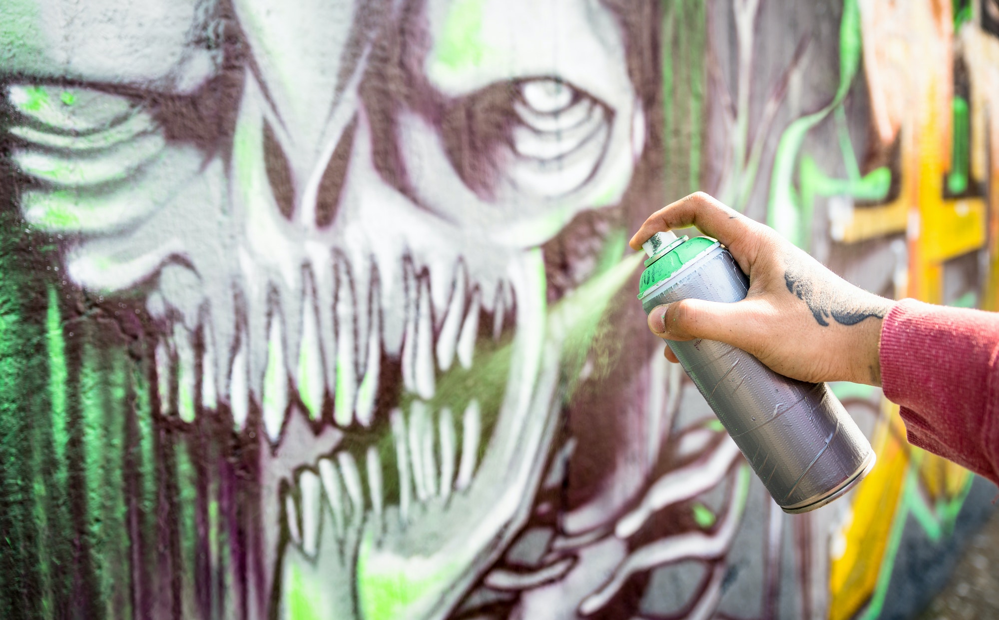 Street artist painting colorful monster graffiti on public wall